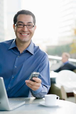 Happy man at computer with phone